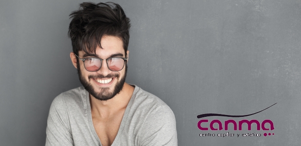 sexy fashion man with beard dressed casual smiling against wall